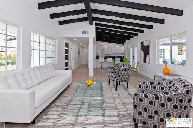 living room with hardwood / wood-style floors, vaulted ceiling with beams, and plenty of natural light