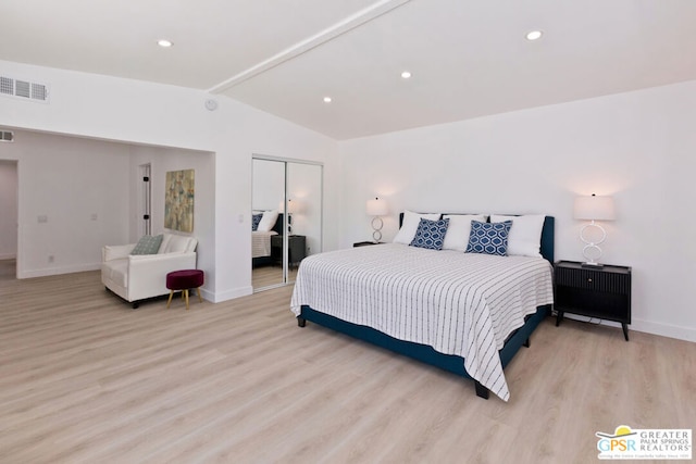 bedroom featuring light wood-type flooring, vaulted ceiling, and a closet