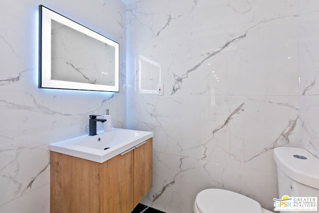 bathroom featuring vanity, toilet, and tile walls