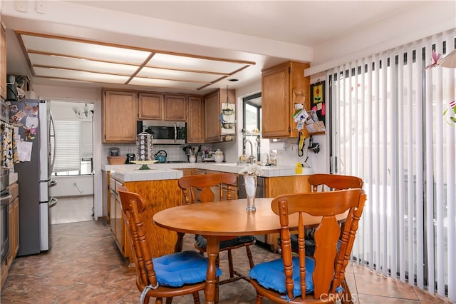 kitchen featuring appliances with stainless steel finishes, a healthy amount of sunlight, kitchen peninsula, and tasteful backsplash