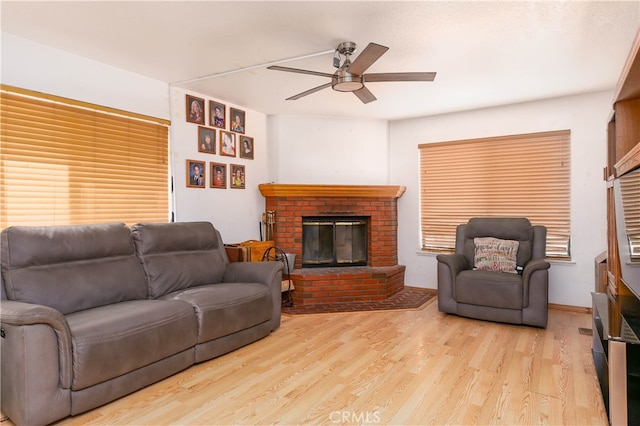 living room with ceiling fan, light wood-type flooring, and a brick fireplace