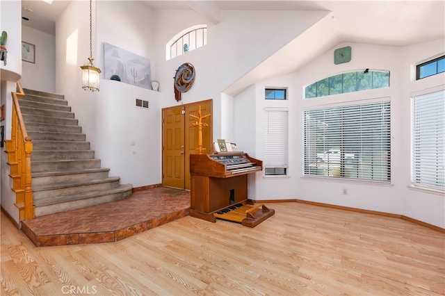 entrance foyer featuring light wood-type flooring, high vaulted ceiling, and a wealth of natural light