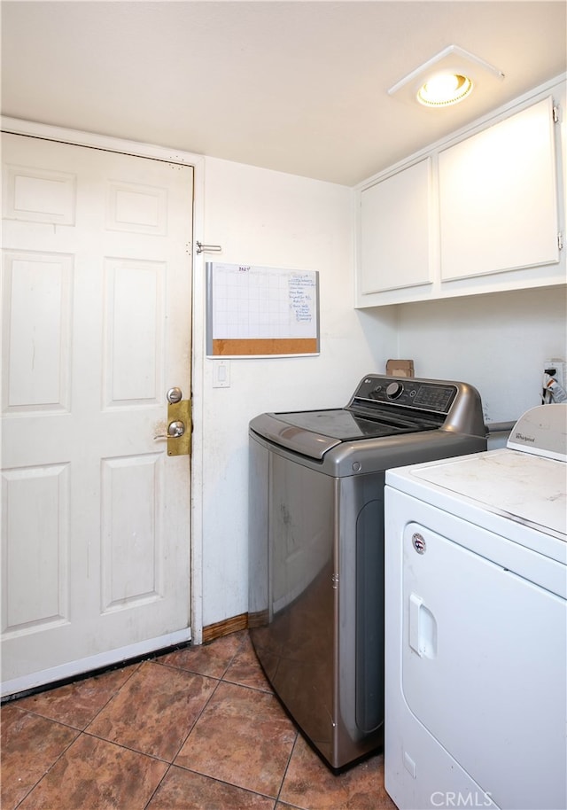 washroom featuring cabinets, dark tile patterned flooring, and washing machine and clothes dryer