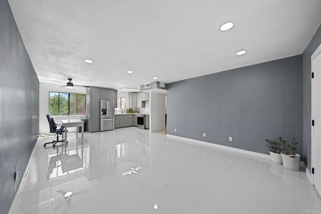 unfurnished living room with a textured ceiling, light tile patterned flooring, and ceiling fan