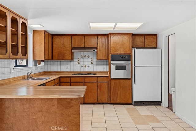 kitchen featuring sink, white fridge, stainless steel oven, gas cooktop, and kitchen peninsula