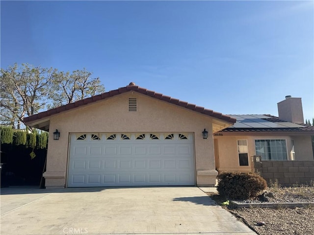 view of front of house featuring concrete driveway, a chimney, stucco siding, solar panels, and a garage