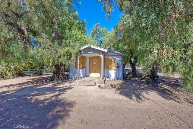 view of front of home featuring an outbuilding and a view of trees