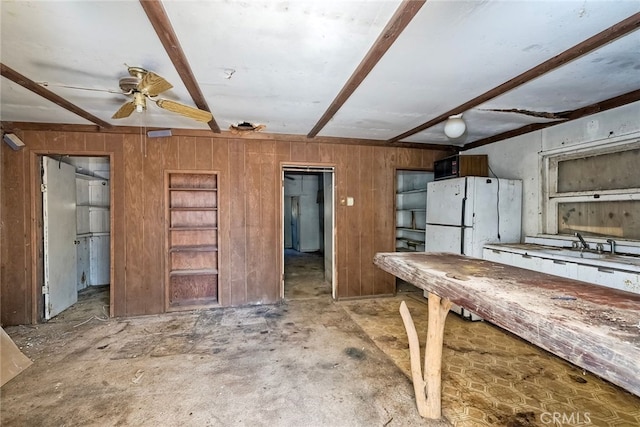 kitchen featuring beam ceiling, ceiling fan, and wood walls