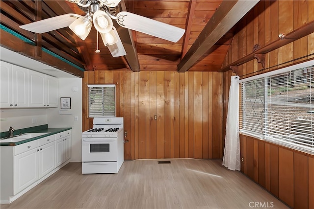 kitchen featuring sink, white cabinets, light hardwood / wood-style flooring, wooden walls, and white range with gas stovetop