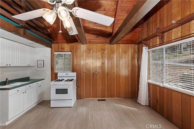 kitchen with wood walls, a sink, light wood-type flooring, wood ceiling, and white range with gas cooktop