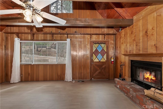 unfurnished living room featuring wood walls, ceiling fan, plenty of natural light, and a fireplace