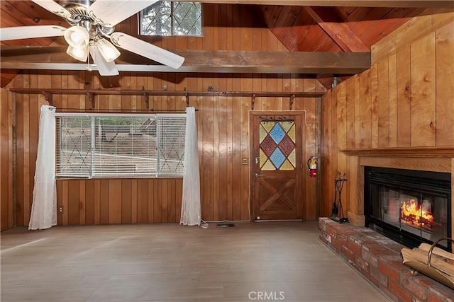 unfurnished living room featuring a fireplace, wood walls, wood ceiling, and vaulted ceiling with beams