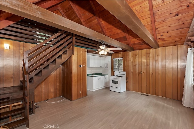 interior space featuring wooden walls, light hardwood / wood-style floors, lofted ceiling with beams, and sink