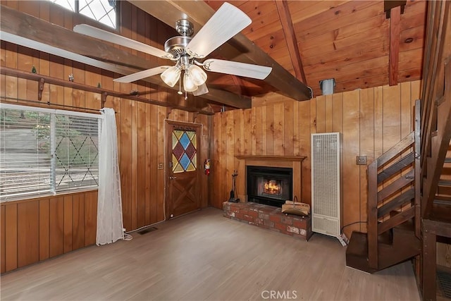 unfurnished living room featuring wooden walls, wood finished floors, a ceiling fan, wood ceiling, and a brick fireplace