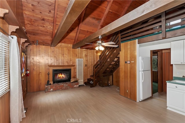 unfurnished living room with light hardwood / wood-style flooring, wood walls, vaulted ceiling with beams, and wooden ceiling