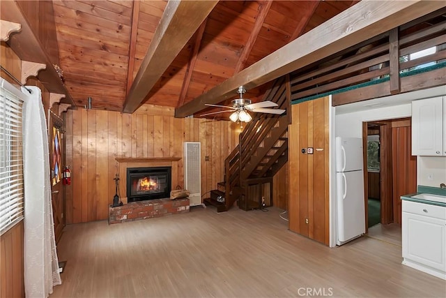 unfurnished living room featuring light wood finished floors, ceiling fan, wooden walls, and wood ceiling