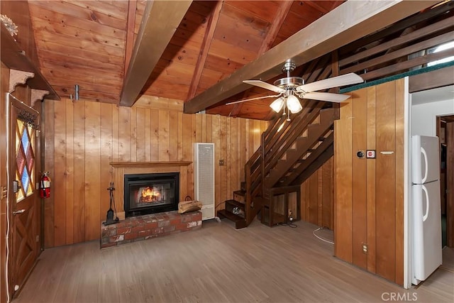 unfurnished living room with a ceiling fan, wood finished floors, wooden walls, a fireplace, and wooden ceiling