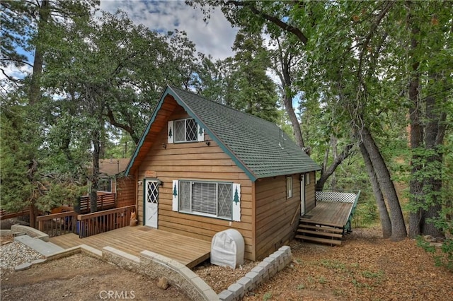 exterior space featuring roof with shingles and a deck