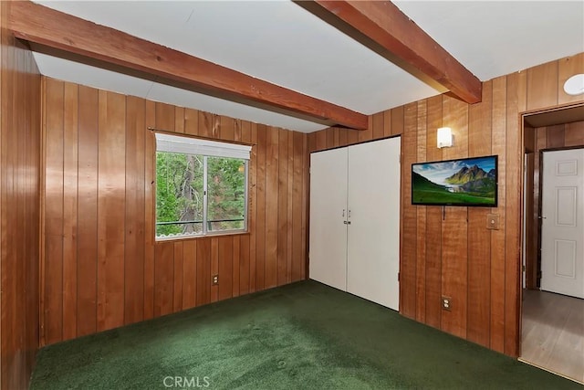 interior space with dark carpet, beam ceiling, and wood walls