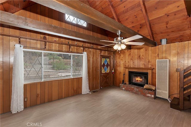 unfurnished living room with ceiling fan, a brick fireplace, wood walls, and light hardwood / wood-style floors