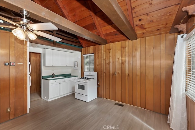 kitchen with lofted ceiling with beams, dark hardwood / wood-style flooring, and gas range gas stove