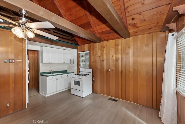 kitchen with gas range gas stove, visible vents, white cabinetry, a ceiling fan, and wood walls