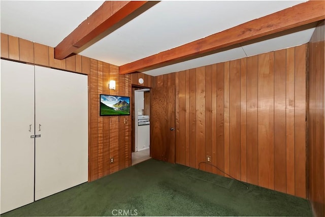 unfurnished bedroom with beamed ceiling, carpet, and wood walls