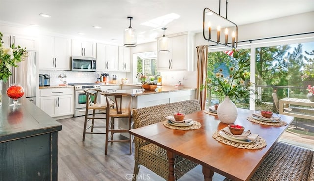 dining area featuring an inviting chandelier, a healthy amount of sunlight, hardwood / wood-style floors, and sink