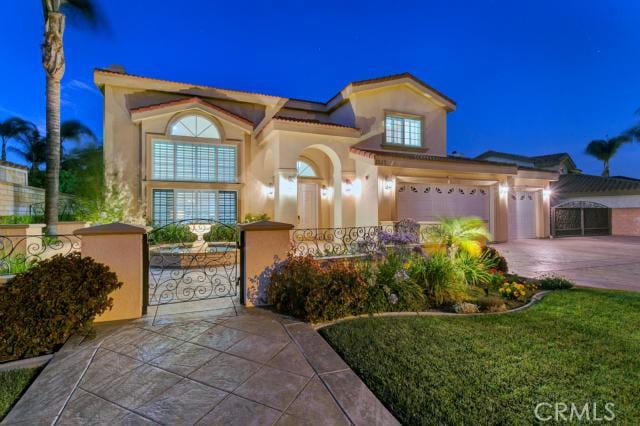 mediterranean / spanish-style home featuring a lawn and a garage