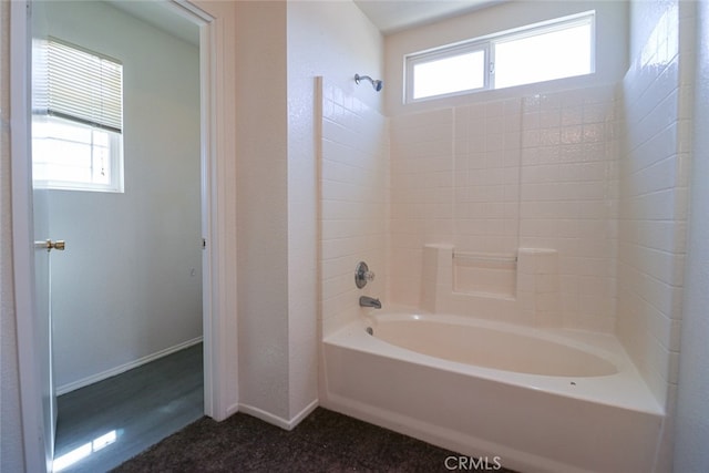 bathroom featuring hardwood / wood-style flooring, washtub / shower combination, and a wealth of natural light