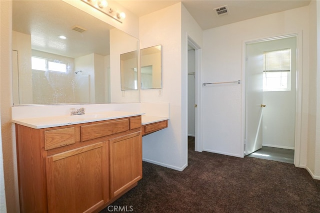 bathroom featuring walk in shower, vanity, and plenty of natural light