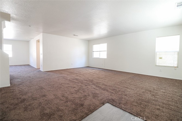 carpeted empty room featuring a textured ceiling