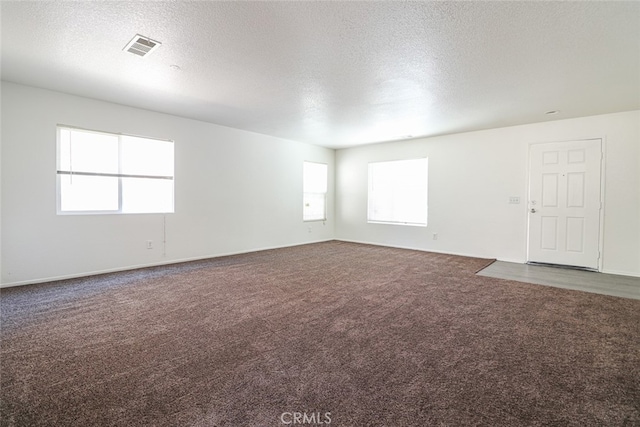 empty room with carpet and a textured ceiling