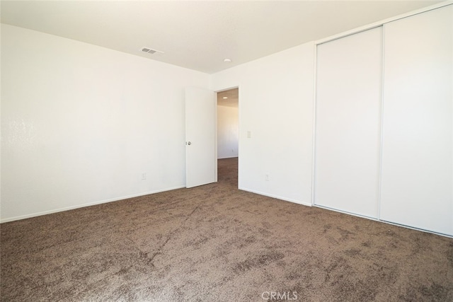 unfurnished bedroom featuring dark carpet and a closet