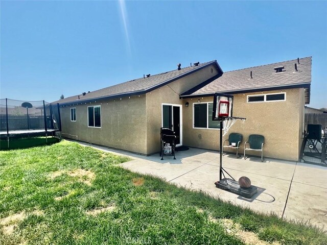 rear view of house featuring a yard, a patio, and a trampoline