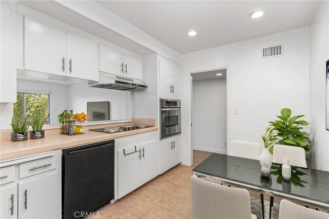 kitchen with black appliances, white cabinetry, light tile patterned floors, and tile counters