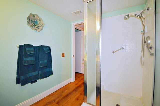 bathroom with hardwood / wood-style flooring and a shower with door