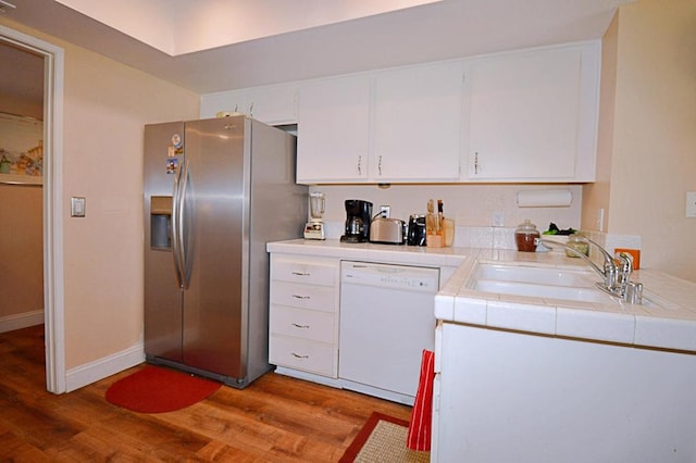 kitchen with dishwasher, sink, stainless steel refrigerator with ice dispenser, light hardwood / wood-style floors, and white cabinets