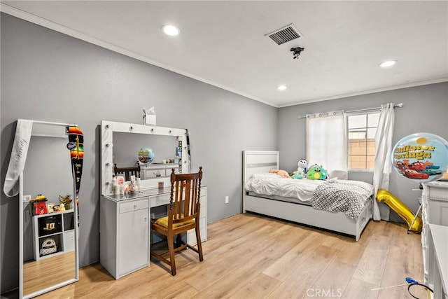 bedroom with ornamental molding and light hardwood / wood-style floors