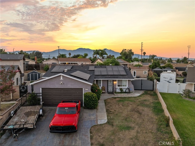 view of front of house with a mountain view, a garage, solar panels, and a lawn