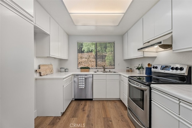 kitchen with sink, white cabinetry, appliances with stainless steel finishes, range hood, and light wood-type flooring