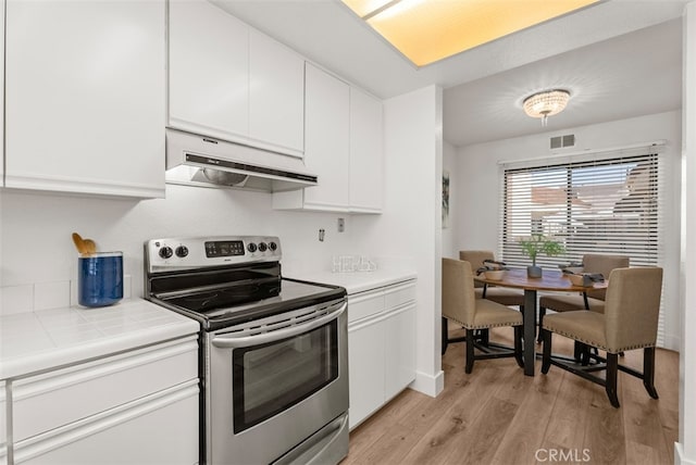 kitchen featuring electric stove, light hardwood / wood-style floors, tile countertops, and white cabinetry