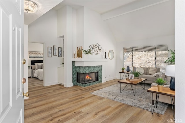 living room featuring beam ceiling, a premium fireplace, hardwood / wood-style floors, and high vaulted ceiling