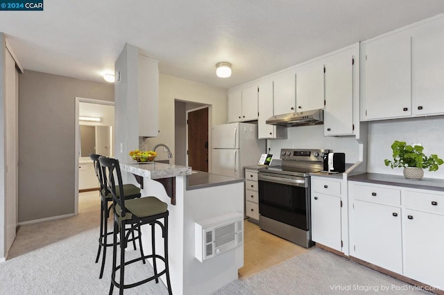 kitchen featuring white cabinets, white fridge, electric range, and a kitchen bar