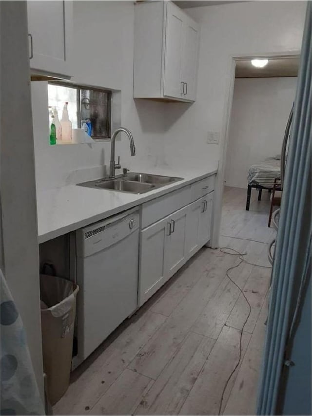 kitchen featuring dishwasher, white cabinets, light wood-type flooring, and sink