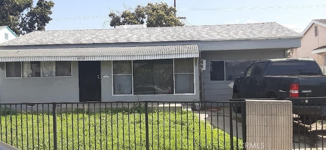 view of front of property with a fenced front yard, roof with shingles, and stucco siding