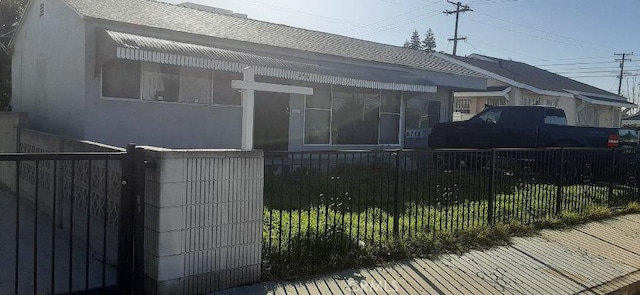 view of home's exterior with a fenced front yard, roof with shingles, and stucco siding