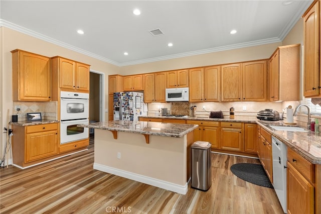 kitchen with light wood-type flooring, a center island, sink, white appliances, and crown molding