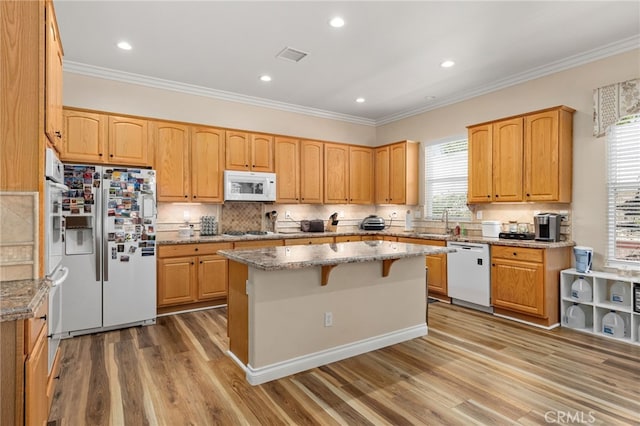 kitchen featuring hardwood / wood-style flooring, a center island, white appliances, and a wealth of natural light