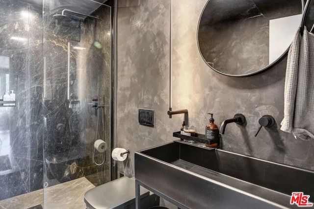 bathroom with a tile shower, sink, and tile walls